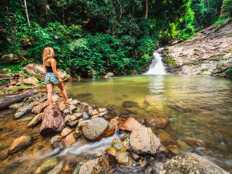 Girl,Standing,And,Looking,At,A,Waterfall,And,Small,Pool